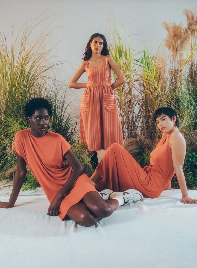 Three models wearing orange dresses from Armedangels