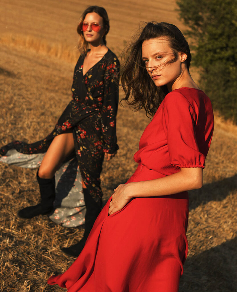 Two models wearing a long black floral dress and long red dress from Souldaze Collection