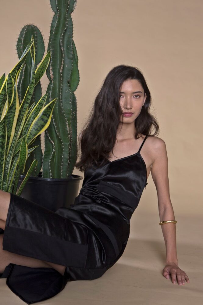 Model wearing a black sleeveless satin midi dress from ARIELLE