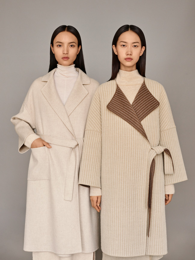 Two models wearing long off-white and beige coats from ICICLE