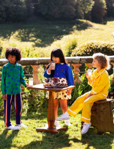 Three children wearing blue, orange and yellow clothes from Mini Rodini
