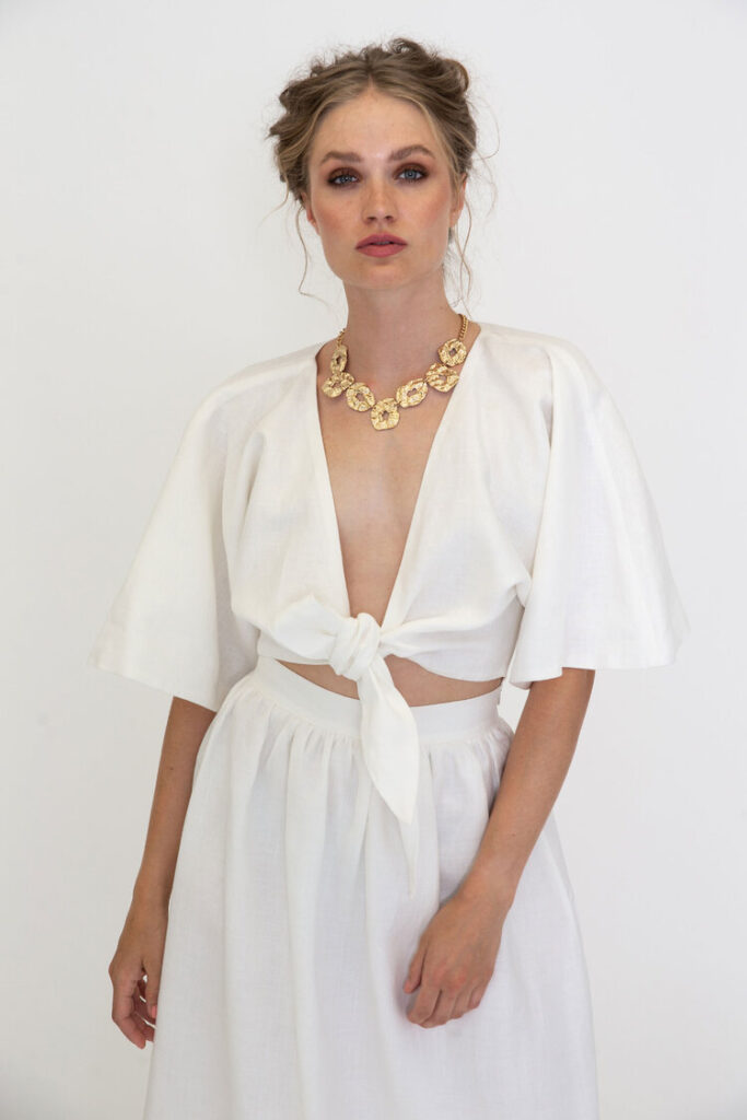 Model wearing a white wrap top and white wide pants from SANIKAI
