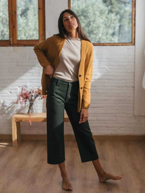 Model wearing ochre yellow cardigan and off-white sweater and dark green cropped pants from TWOTHIRDS