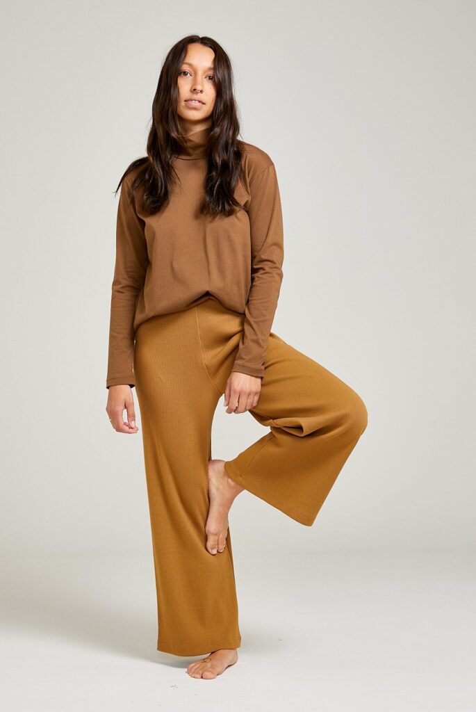 Model wearing a brown longsleeve turtleneck sweater and ochre yellow wide pants from Vege Threads