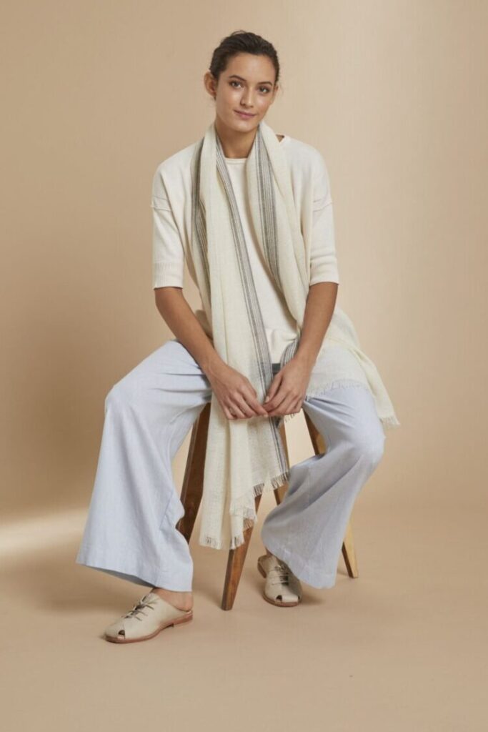 Model wearing light blue pants and an off-white top and scarf from animana