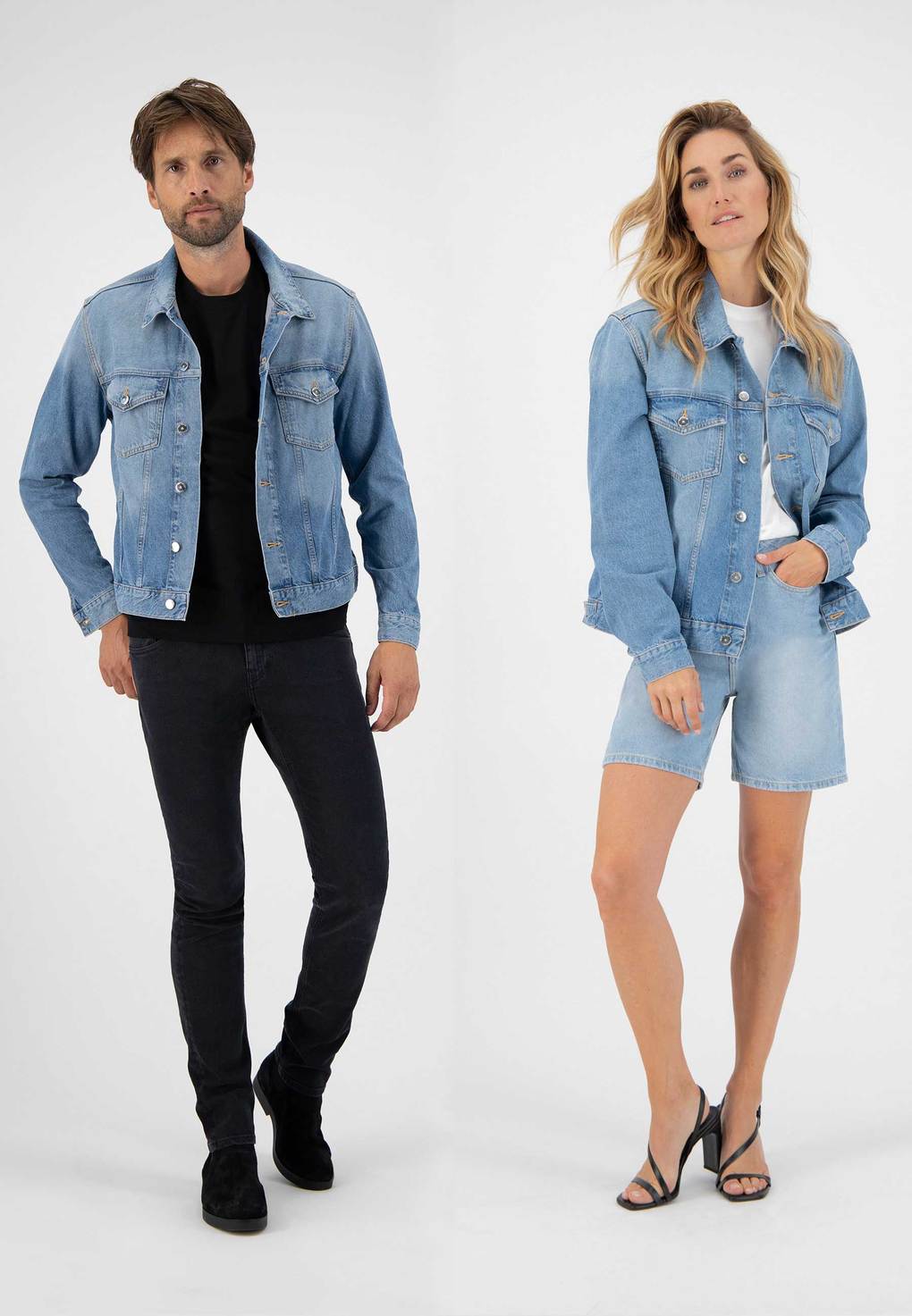Male and female model wearing light blue denim jackets and black skinny jeans and light blue denim long shorts from MUD Jeans