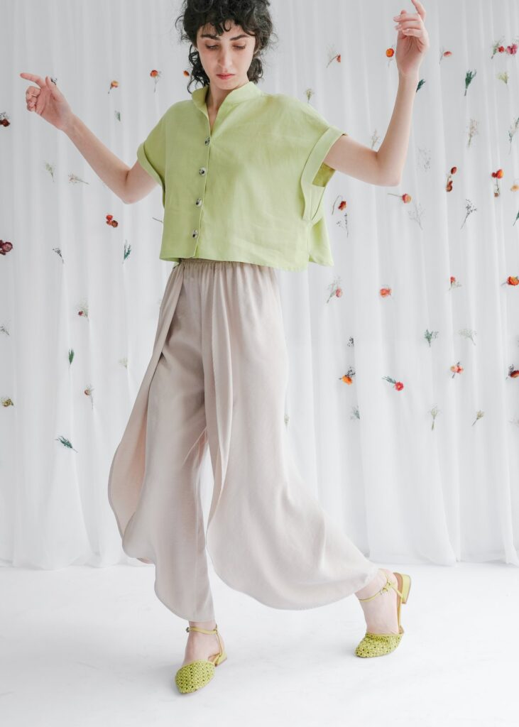 Model wearing a light green button up crop top and wide off-white pants from OhSevenDays with green shoes