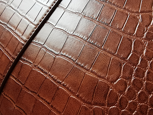 Zoomed in picture of a brown crocodile PU leather bag