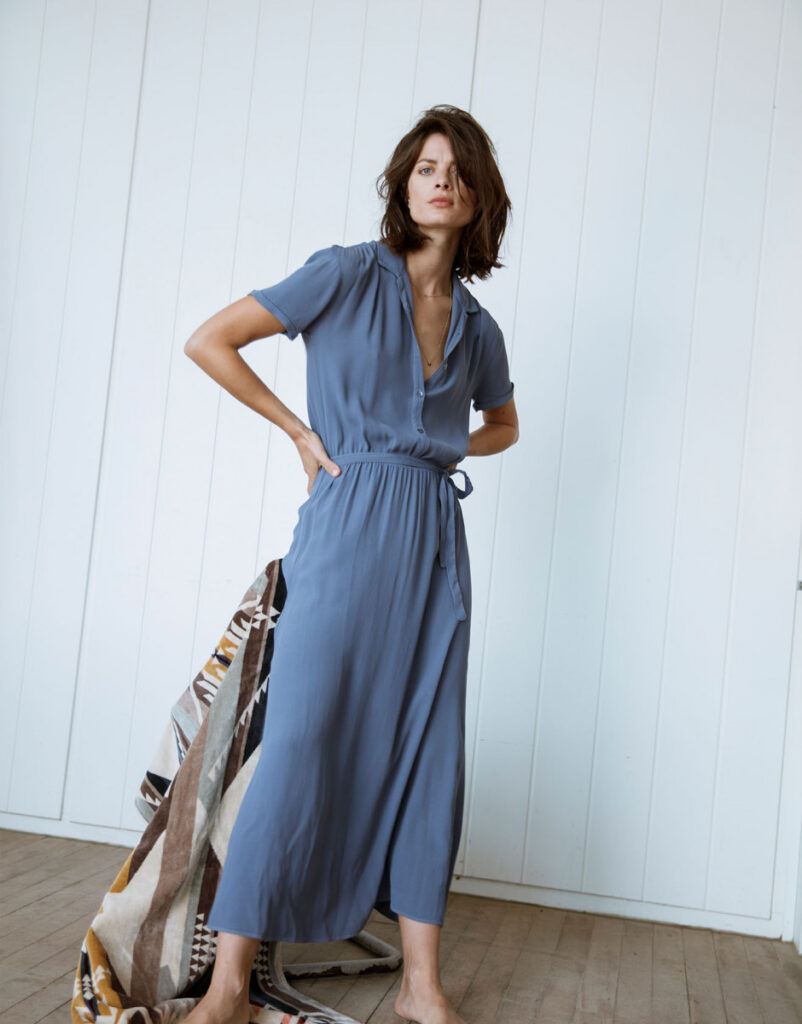 Model wearing a long blue dress with short sleeves from Alchemist
