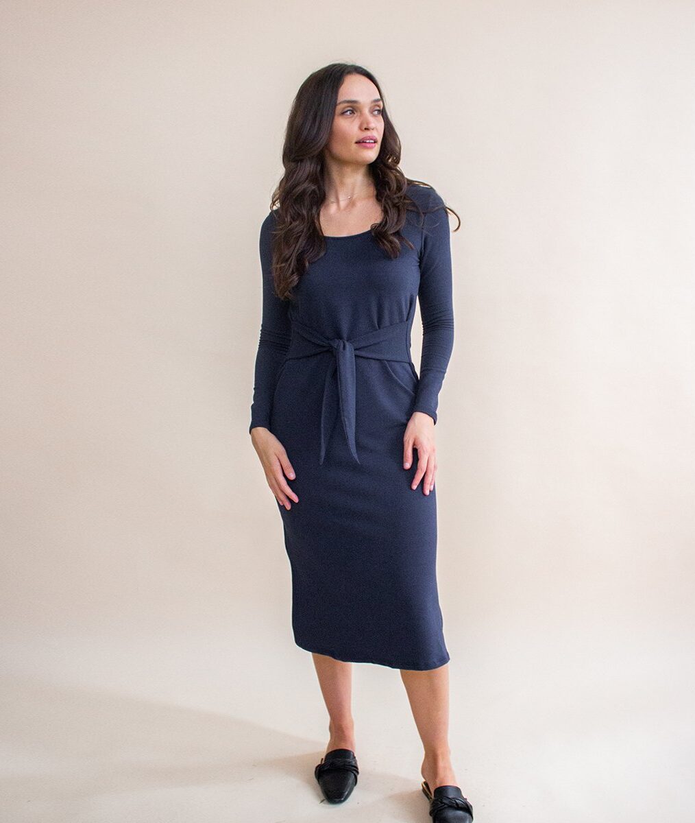 Model wearing a midi length dark blue tight dress with long sleeves from Encircled with black shoes