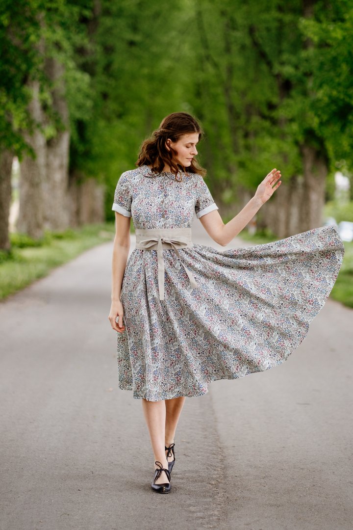 Model wearing a grey printed midi dress and a thick fabric belt from Son de Flor with black shoes, in the middle of a road