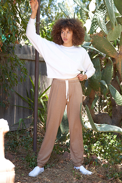 Model wearing beige sweatpants and a white sweater from sustainable brand LA Relaxed