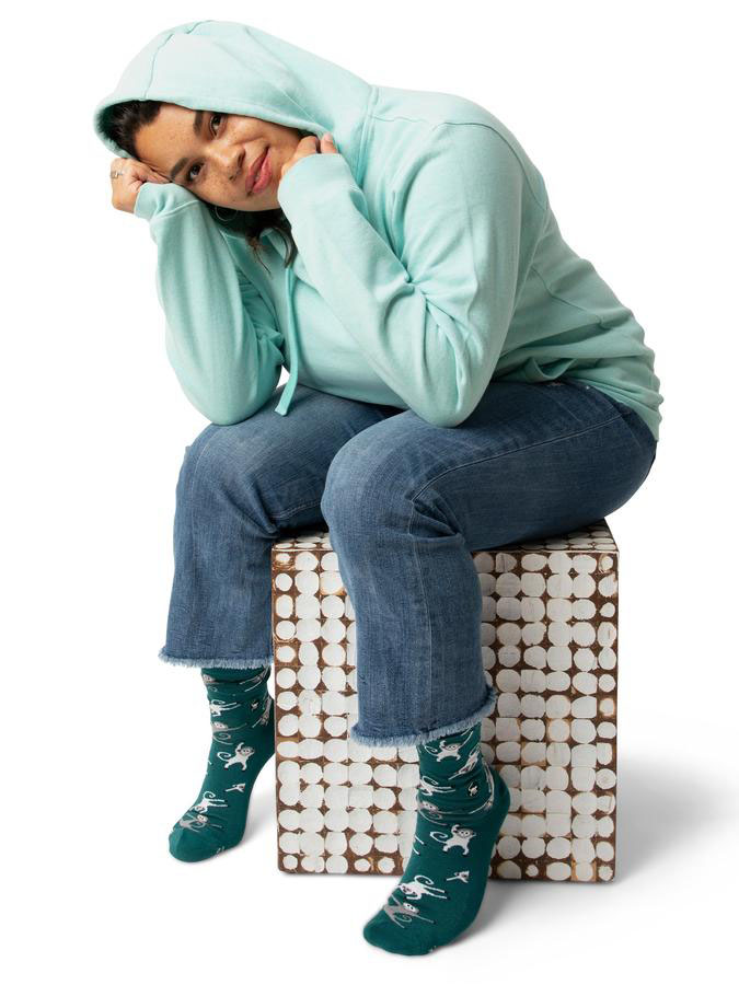 Model wearing dark green socks with a print, and a baby blue hoodie from sustainable brand Conscious Step