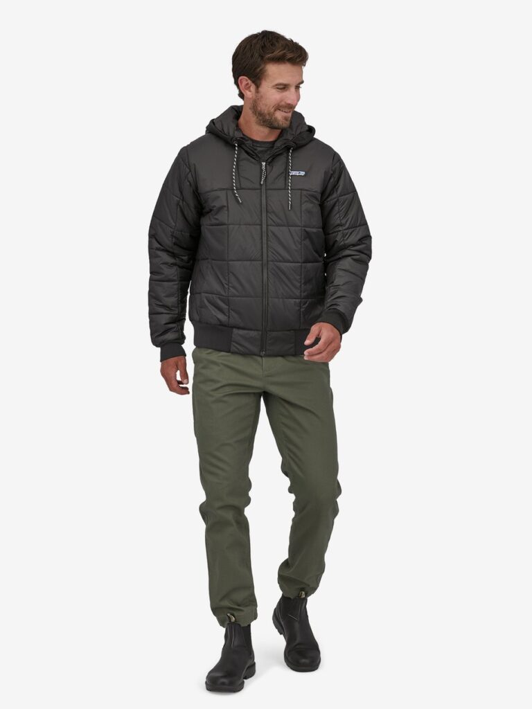 Male model wearing a black puffer jacket from Patagonia with dark green pants and black boots