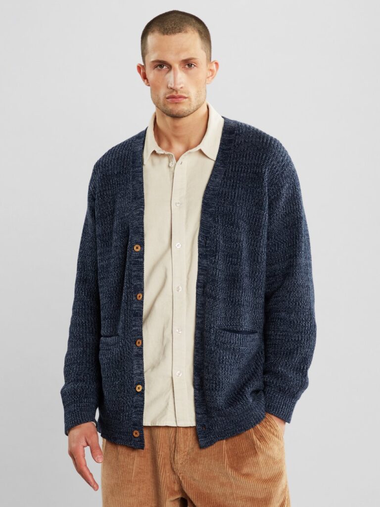 Male model wearing dark blue cardigan with off-white shirt underneath and camel coloured pants from Dedicated