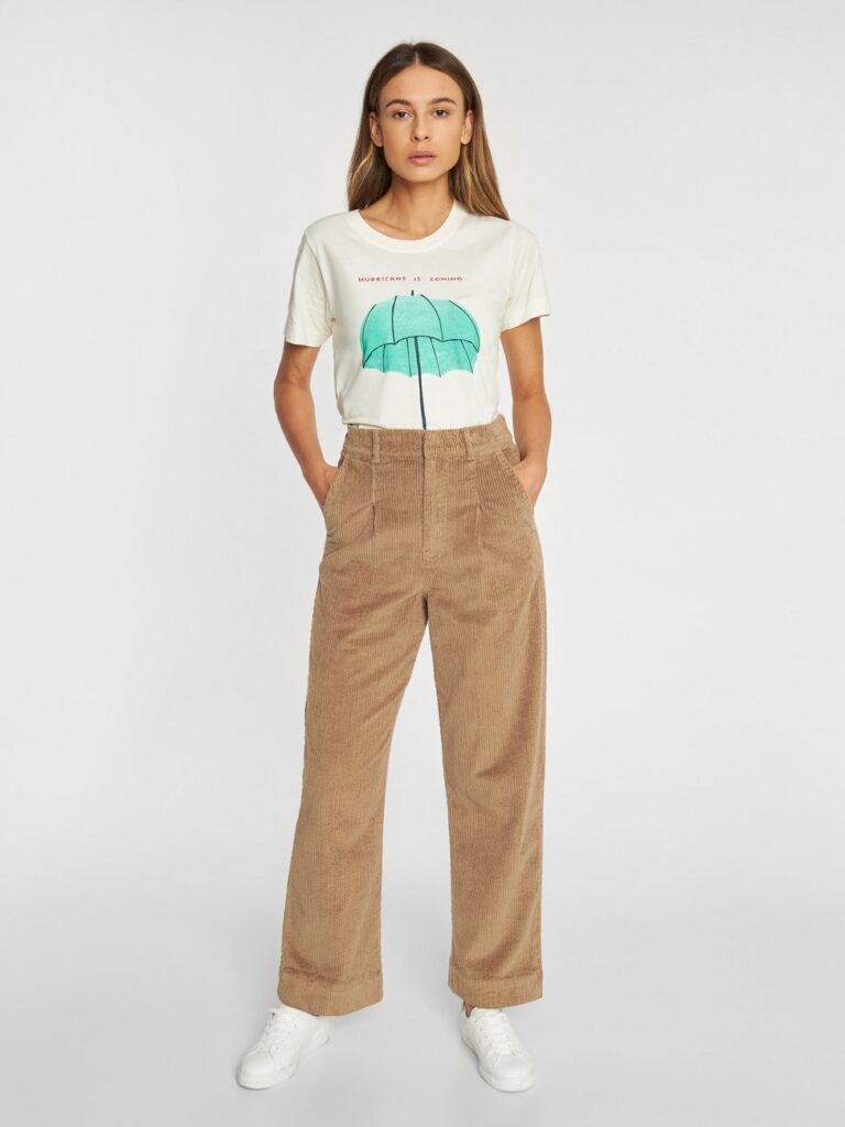 Model wearing beige corduroy wide pants with white graphic T-shirt from Dedicated