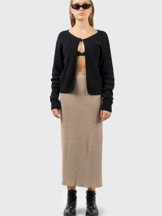 Model wearing a beige knitted midi skirt and a black cardigan from sustainable brand nu-in