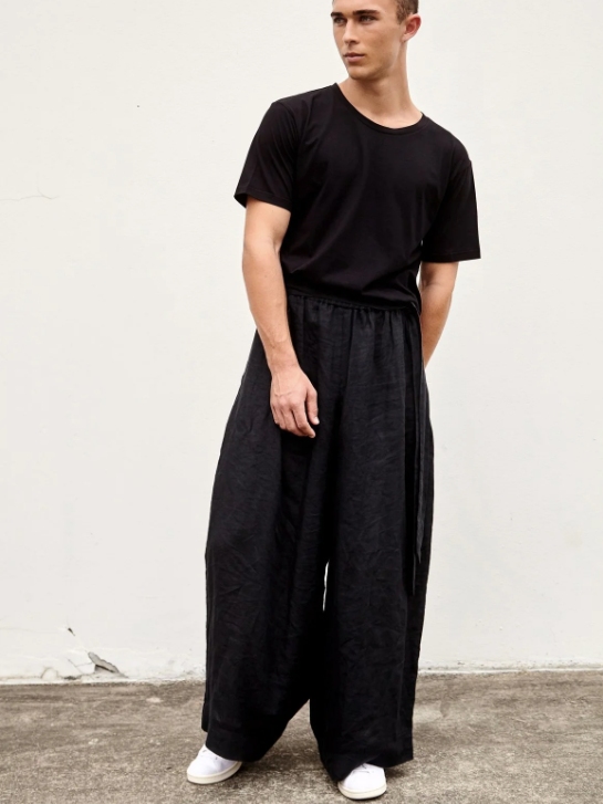 Male model wearing black wide trousers and a black T-shirt from A.BCH with white shoes