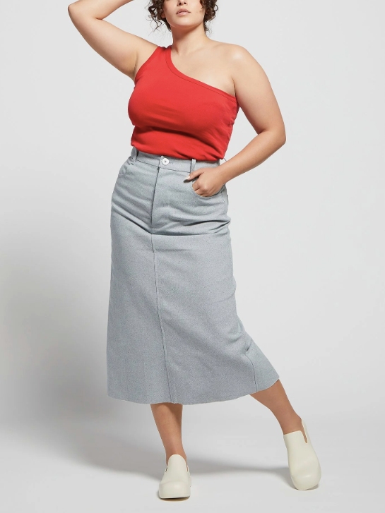 Female model wearing a midi light blue denim skirt with a red tank top from A.BCH with white shoes