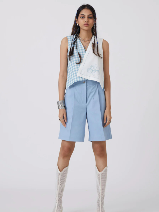 Model wearing light blue long wide shorts and a white and blue crop top from sustainable brand The Summer House