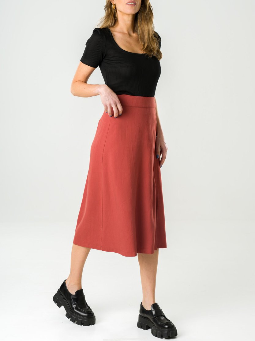 Model wearing a red midi skirt and a black T-shirt from sustainable brand Avani