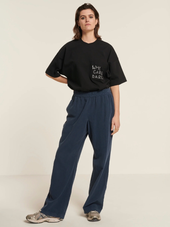 Model wearing dark blue wide leg pants and a black oversized T-shirt from sustainable brand New Optimist