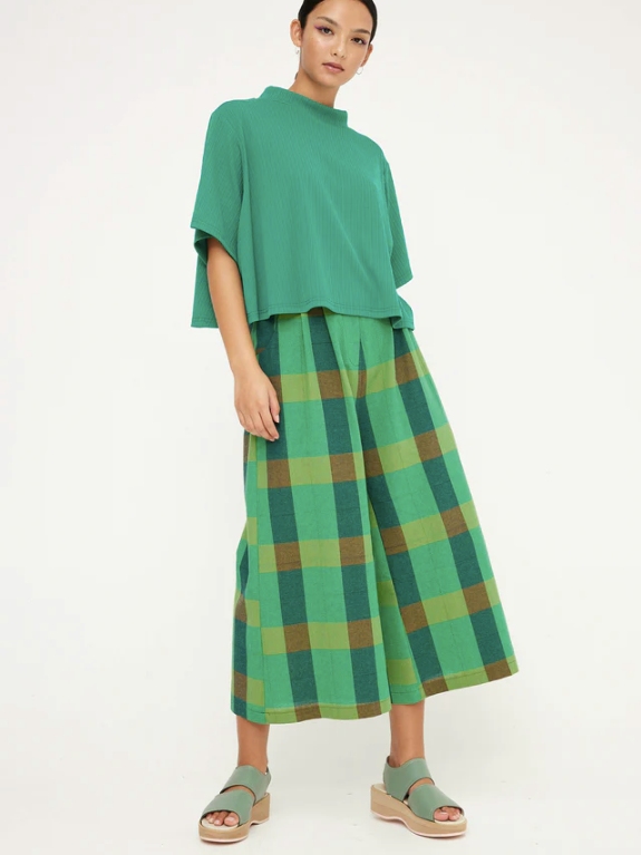 Model wearing green checkered wide leg pants and a green short sleeve top from sustainable brand Kuwaii