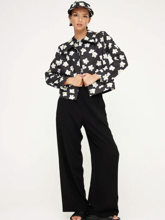 Model wearing black wide leg pants, a black and white floral jacket and a matching hat from sustainable brand Kuwaii