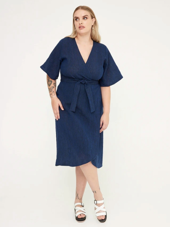Model wearing a blue midi length dress with short sleeves from sustainable brand Kuwaii