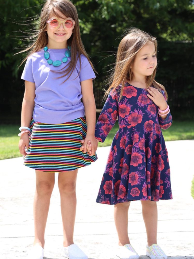 Two little girls wearing clothes from Mightly, standing on a road