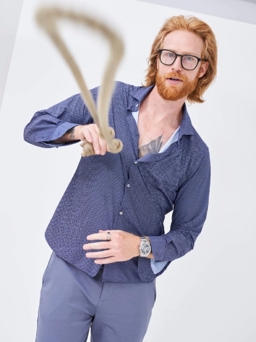 Male model wearing blue pants and a blue button-up shirt from sustainable brand NEEM