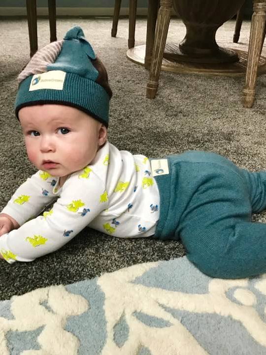 Baby wearing green pants and a matching beanie from sustainable brand Babee Greens